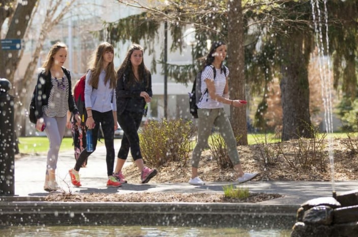 Four female college students walking through campus